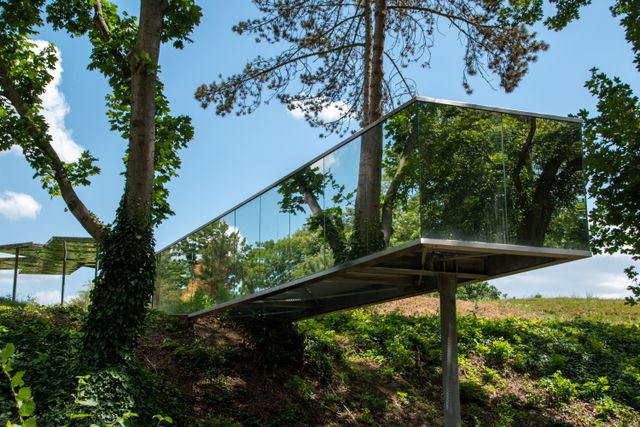 Trees and sky reflected in the glass panels of a building.